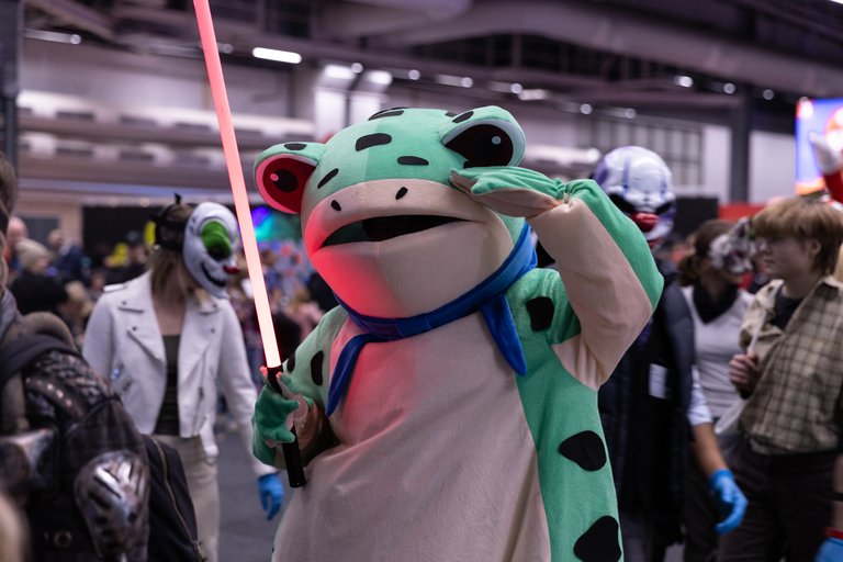 En person är utklädd till en groda och håller i ett lasersvärd på Comic Con i Stockholm.