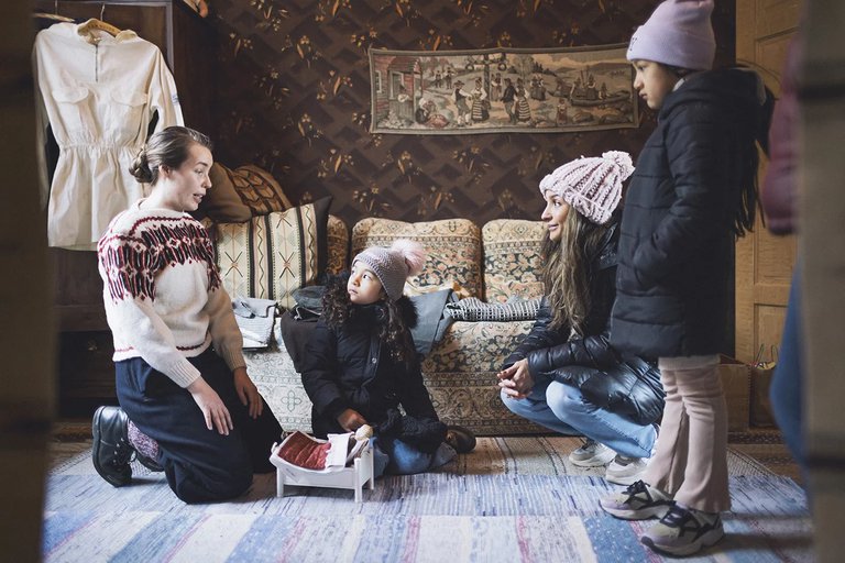 två vuxna och två barn i Jarnhandlarbostaden i Skansen