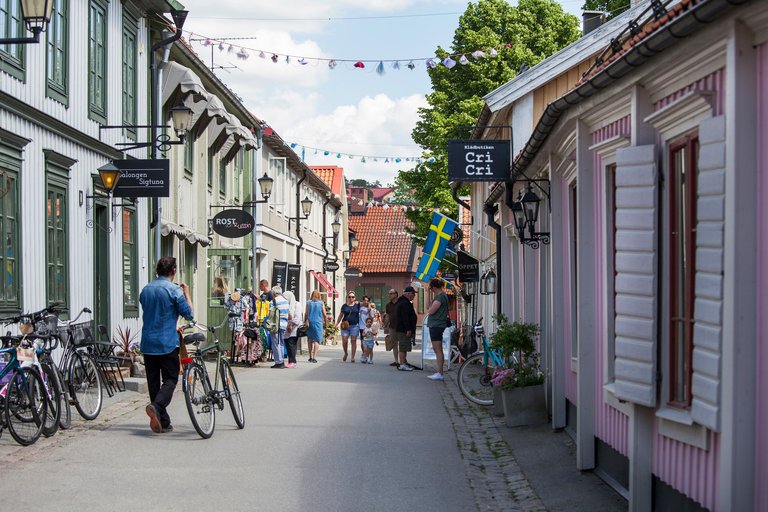 En charmig gågata i Sigtuna kantad av låga trähus i pastellfärger