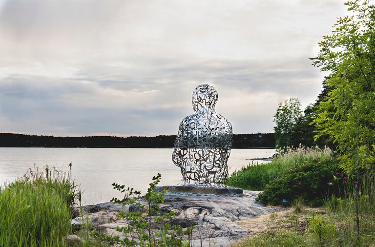 Museer i Stockholm. Artipelag, Gustavsberg. Stockholms skärgårg. På bilden syns Jaume Plensas skulptur "Ainsa IV". Den föreställer en människa som sitter på huk. Skulpturen står i naturen runt Artipelag, där den är en del av konstvandringen.
