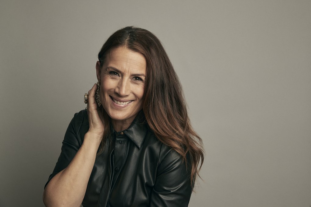 En leende kvinna med halvlångt brunt hår och svart läderjacka.